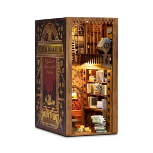 A detailed view of the Eternal Bookstore DIY book nook kit, showcasing a cozy, two-story vintage bookstore with a glowing fireplace, a spiral staircase, and a puppy resting by the fire.