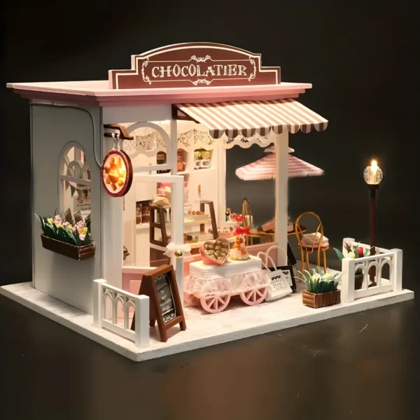 Full view of the Cocoa Fantasy miniature dessert shop, showcasing its pink awning, chocolate cart, and outdoor seating area.