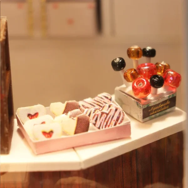 Close-up view of handmade chocolates and candies on a display counter in the Cocoa Fantasy chocolate shop miniature dollhouse kit.