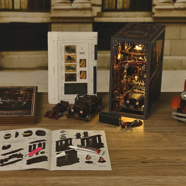 Complete setup of the Car Players DIY Book Nook Kit, featuring all assembly tools, miniature vehicles, and instruction booklets laid out on a wooden table, set against a vintage automotive backdrop.