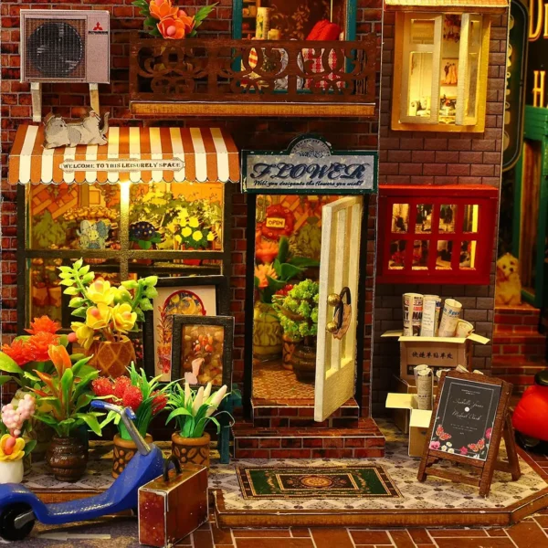 Close-up of a flower shop entrance at Scarbrough Hotel with vibrant flowers, potted plants, and a striped awning, showcasing the detailed craftsmanship of the DIY miniature dollhouse kit.