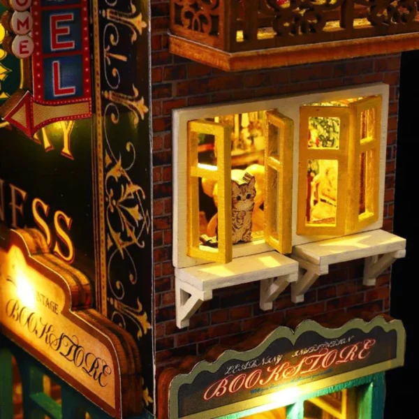 Close-up of a warmly lit window in Scarbrough Hotel DIY miniature dollhouse kit, featuring a kitten looking out, with a vintage bookstore sign below.