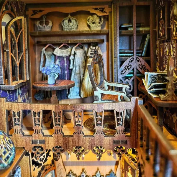 Close-up of the second floor of the book nook, featuring crowns, a dress, a bookshelf, and a reading desk.