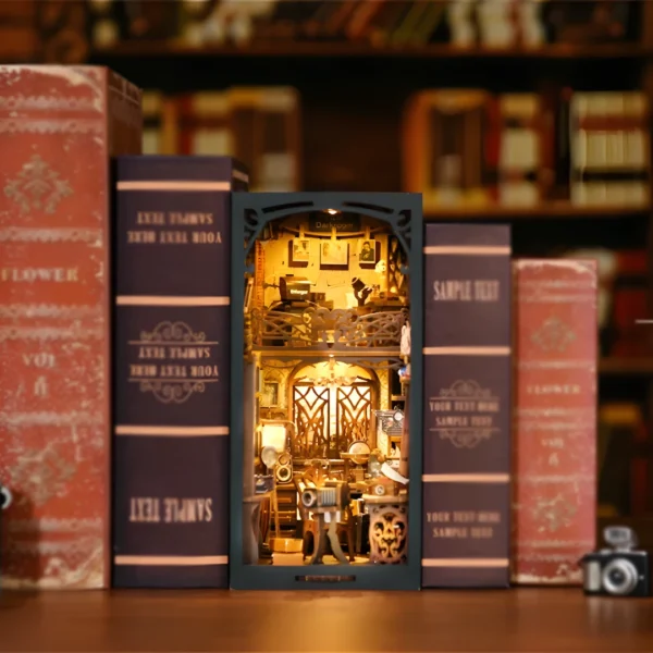 A front view of the Film Darkroom DIY Book Nook kit showcasing vintage cameras, a film projector, and a photographer's workspace, all arranged in a nostalgic, warmly lit setting.