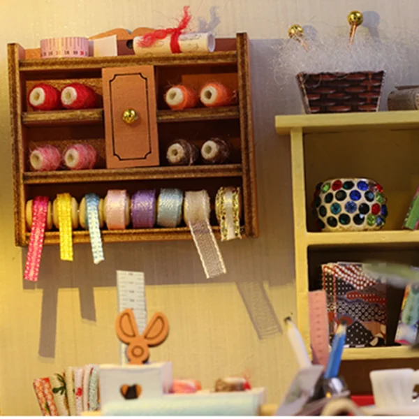 Close-up of tailor shop’s ribbon and fabric storage shelf with colorful ribbons and neatly rolled fabrics in this delightful diy miniature dollhouse kit.